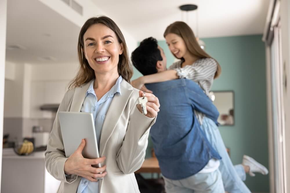 Insurance agent handing over house keys to happy clients, demonstrating the customer service, trust, and relationship-building skills needed to become a successful insurance agent.